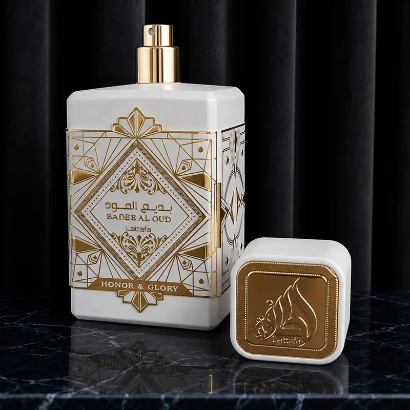 Gold spray nozzle atomizer uncovered next to a heavy white cap engraved with the golden Lattafa logo.